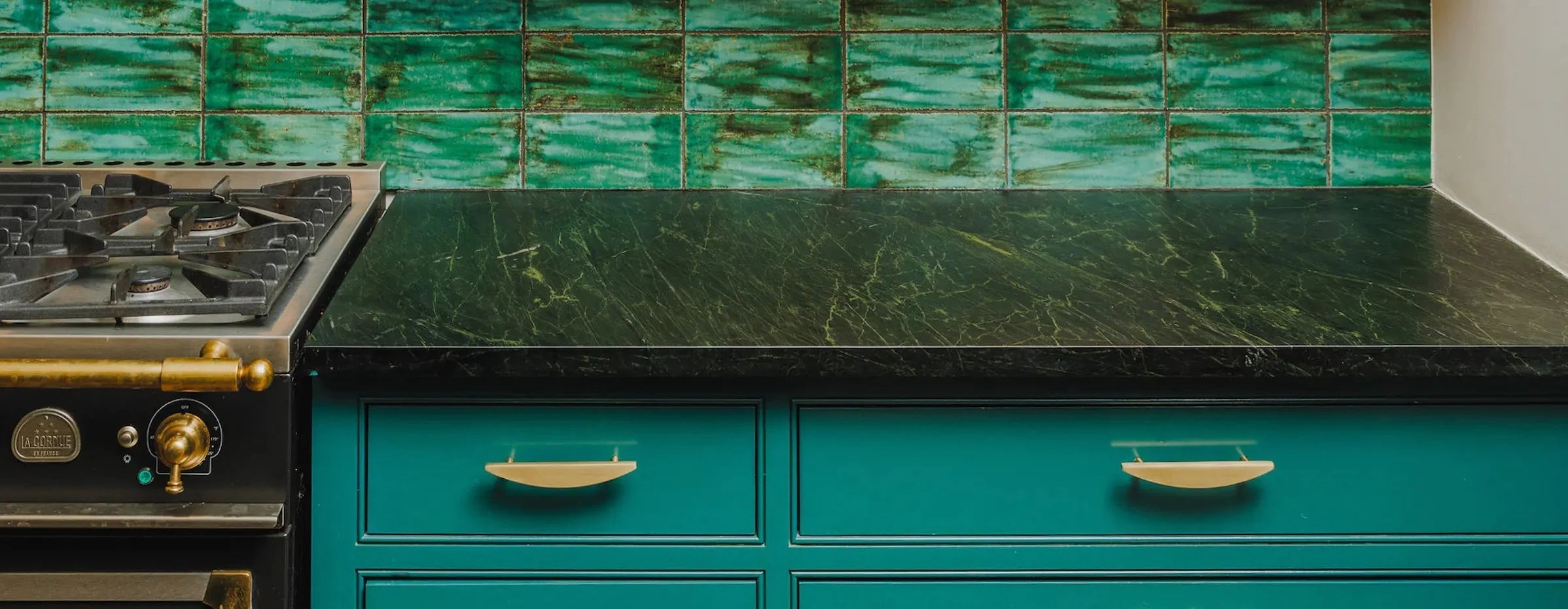 Modern kitchen stovetop with blue drawers and cabinet pulls in satin brass finish