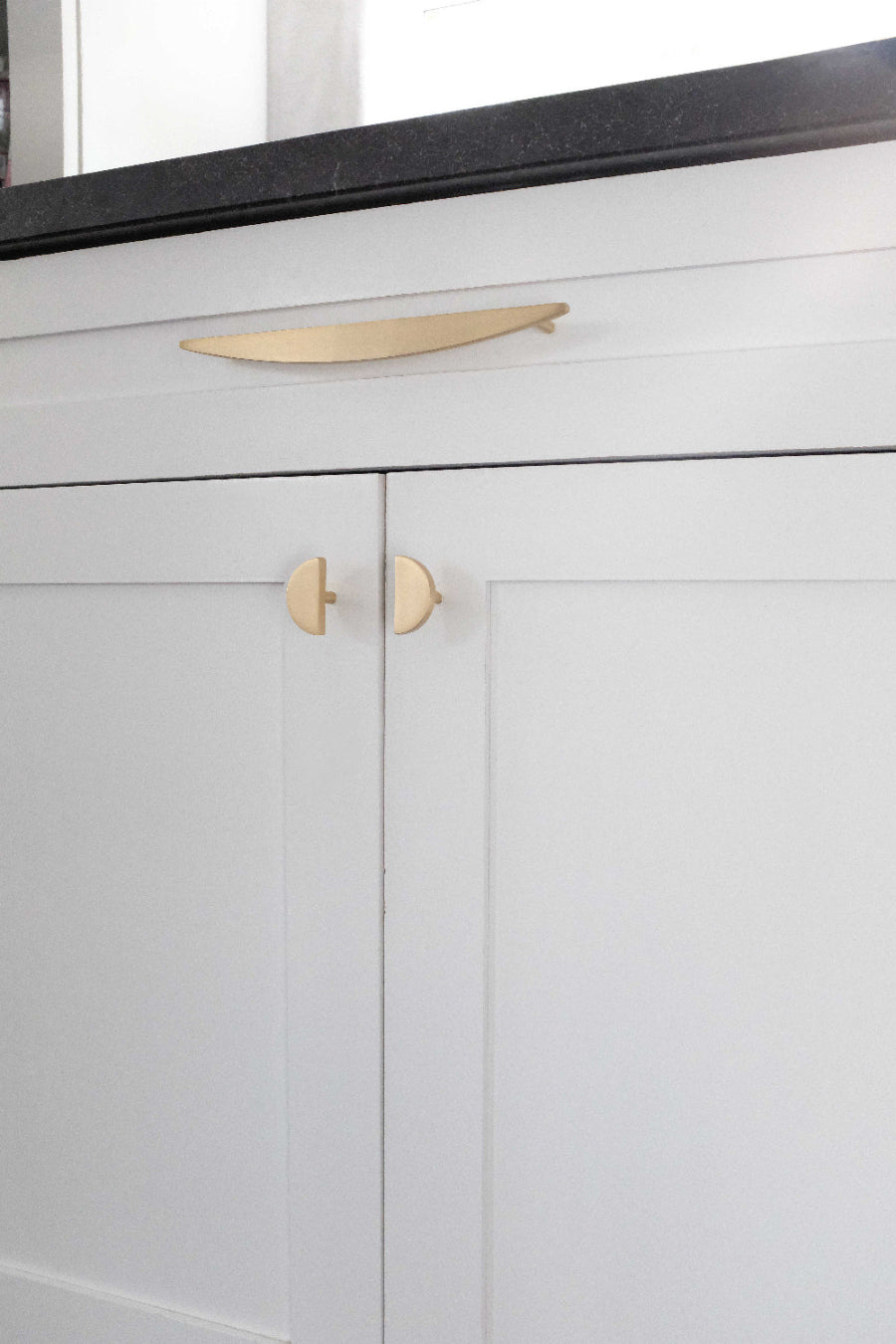 Half moon pull and knobs in satin brass for modern white cabinets