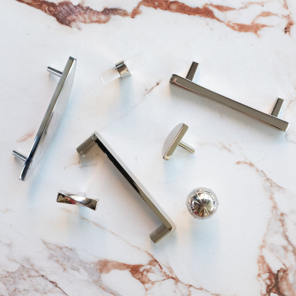 Modern cabinet pulls and knobs in polished nickel on white marble counter for contemporary kitchens and bathrooms
